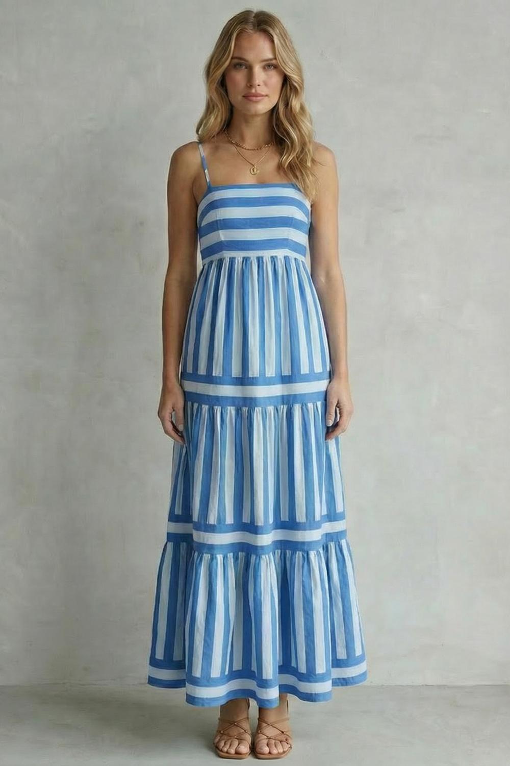 Full shot of a woman modeling a blue and white striped strappy tiered maxi dress, highlighting the casual elegance.