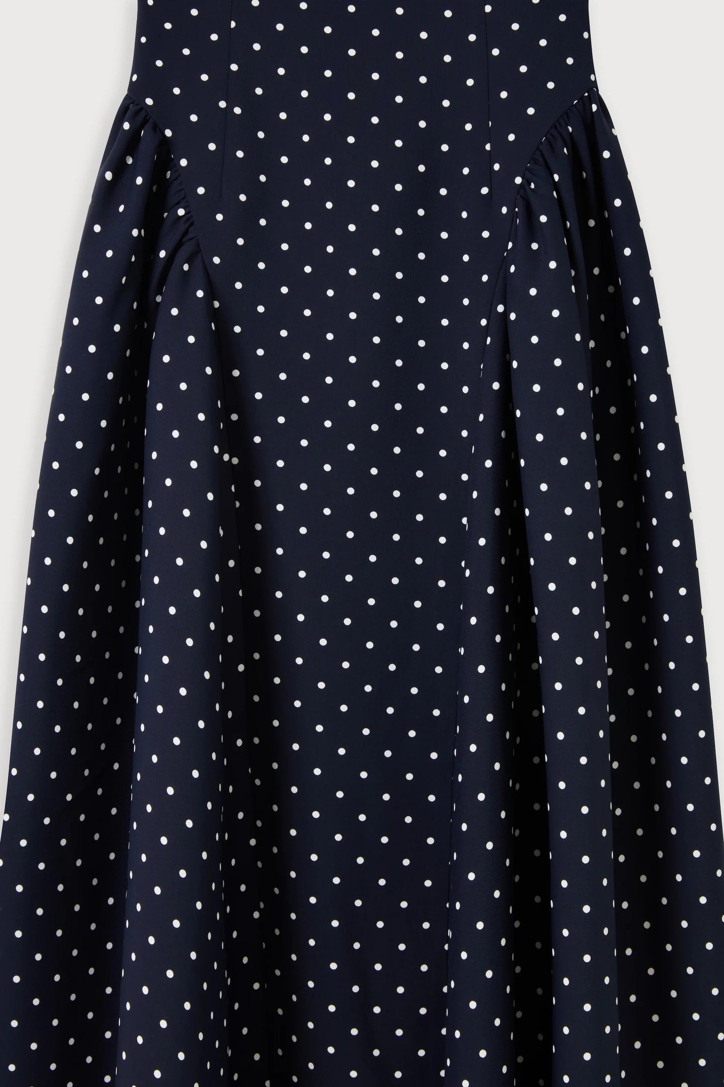 Close-up of gathered hip panels on navy polka dot midi summer dress showing draped fabric detail