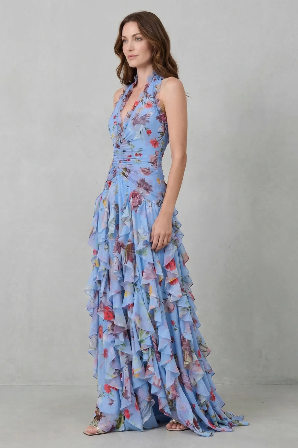Side view of a woman in a light blue floral halter maxi dress, highlighting the elegant flow and tiered ruffles.