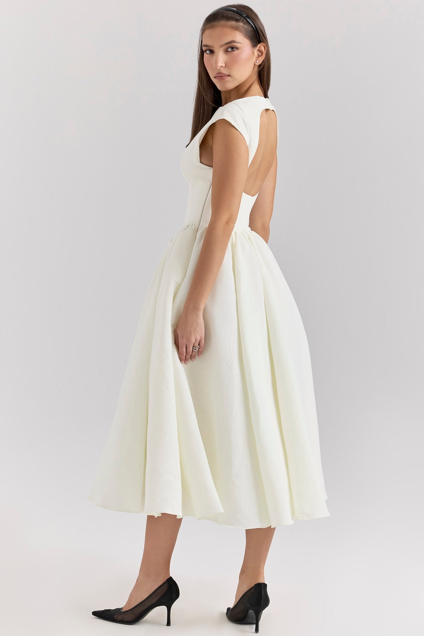 Side profile of a white open back square neck midi dress, showcasing the elegant silhouette and full skirt.