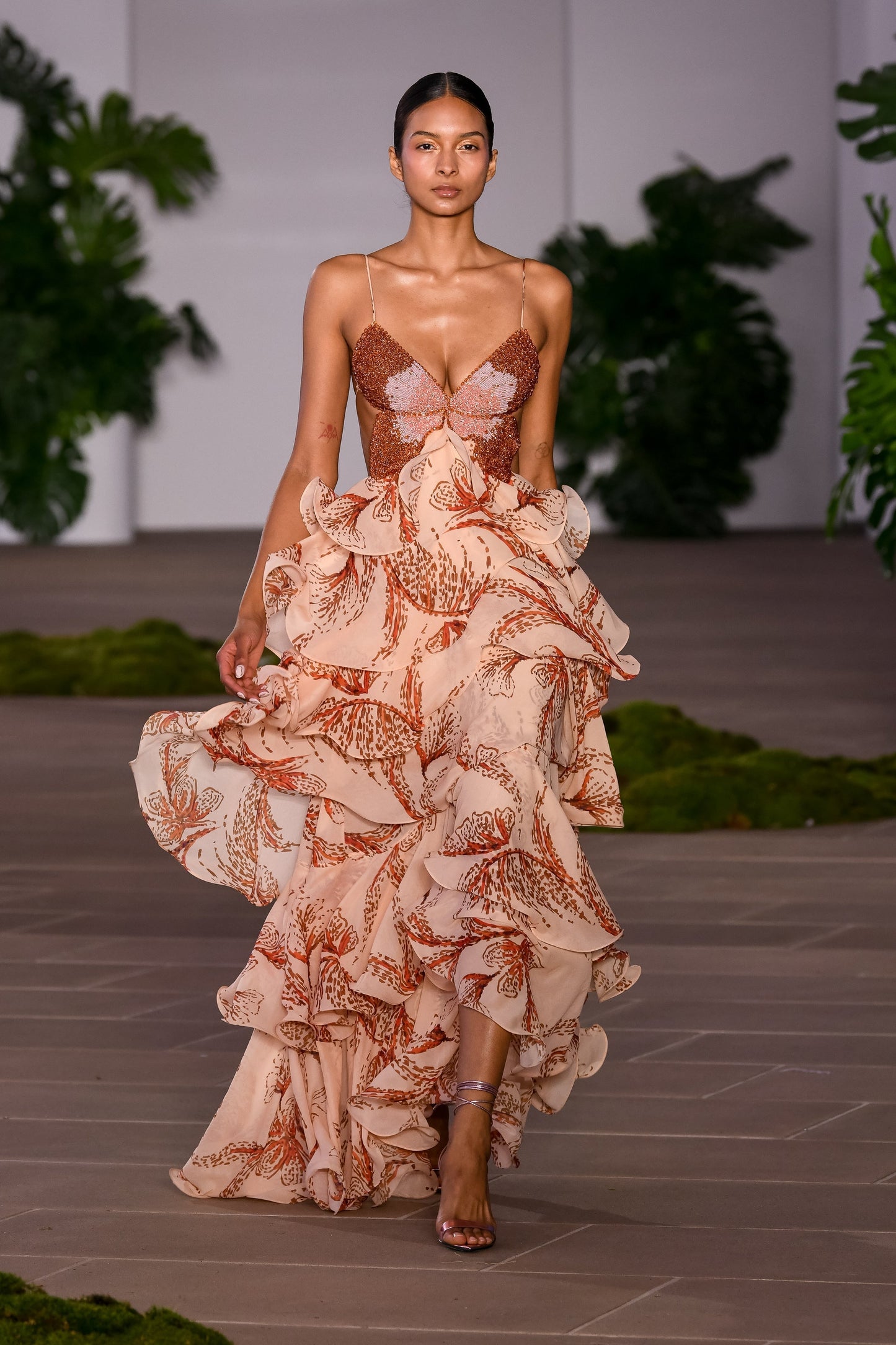 Full-length view of the women's printed beaded butterfly maxi dress with tiered ruffles, worn on a runway.