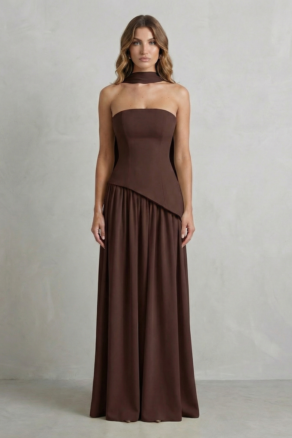 Full-length view of a brown strapless maxi dress featuring a unique draped neck and flowing skirt, ideal for formal events.