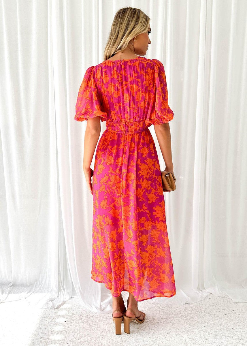 Back view of a women's floral V-neck maxi dress in pink and orange, showcasing the gathered waist and flowing skirt, a beautiful choice for wedding guest dresses.
