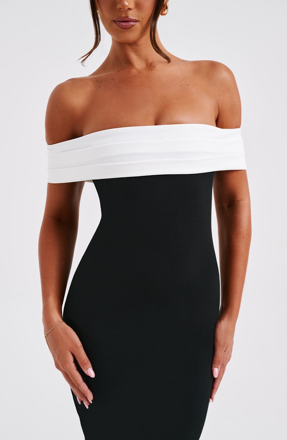 Close-up of the bodice of a black off-shoulder bodycon midi dress with a white folded neckline, elegant for wedding guests.