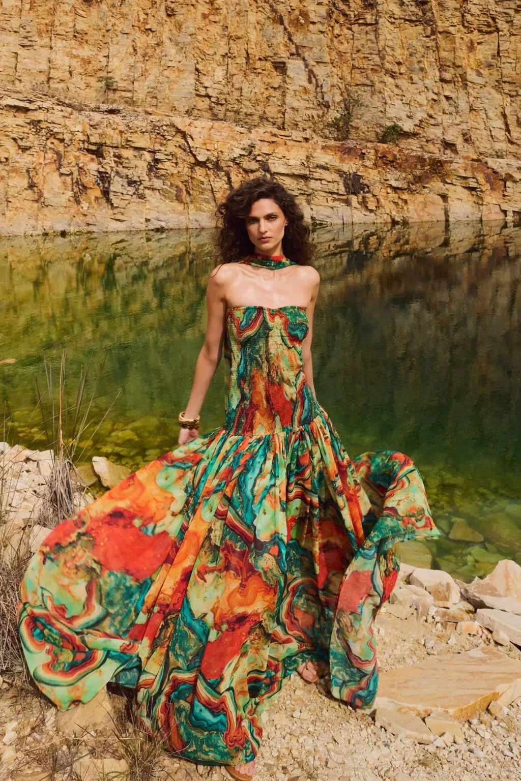 Outdoor shot strapless printed maxi dress with wide sweeping skirt, green red marble print by water