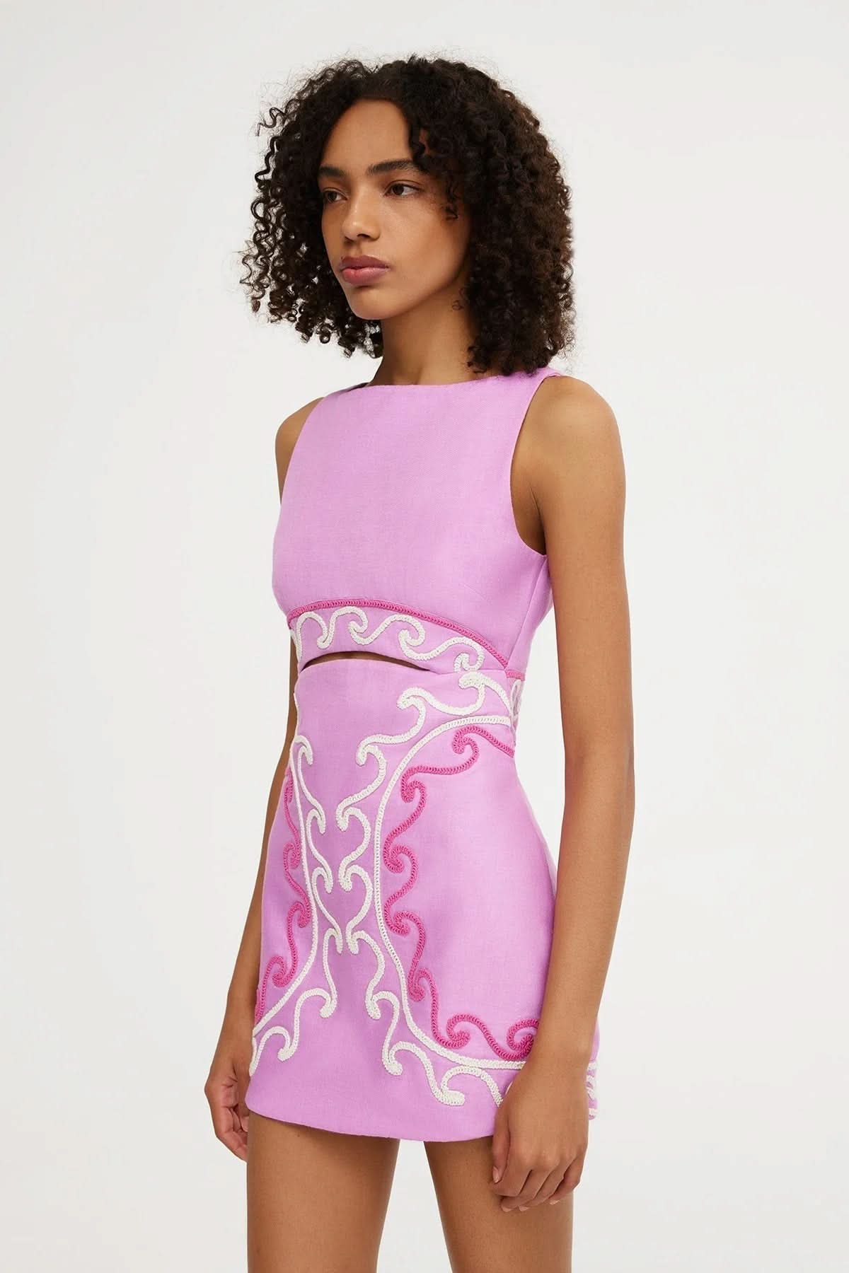 Side profile of a women's sleeveless mini dress in light purple, showcasing the waist cut-out and detailed pink and white embroidery.