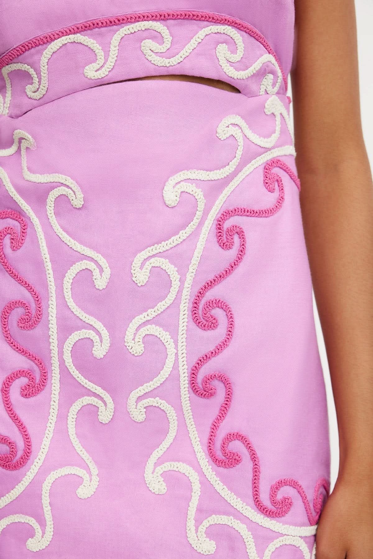 Close-up of the intricate pink and white embroidered swirl patterns on the light purple women's mini dress, highlighting the fabric texture.