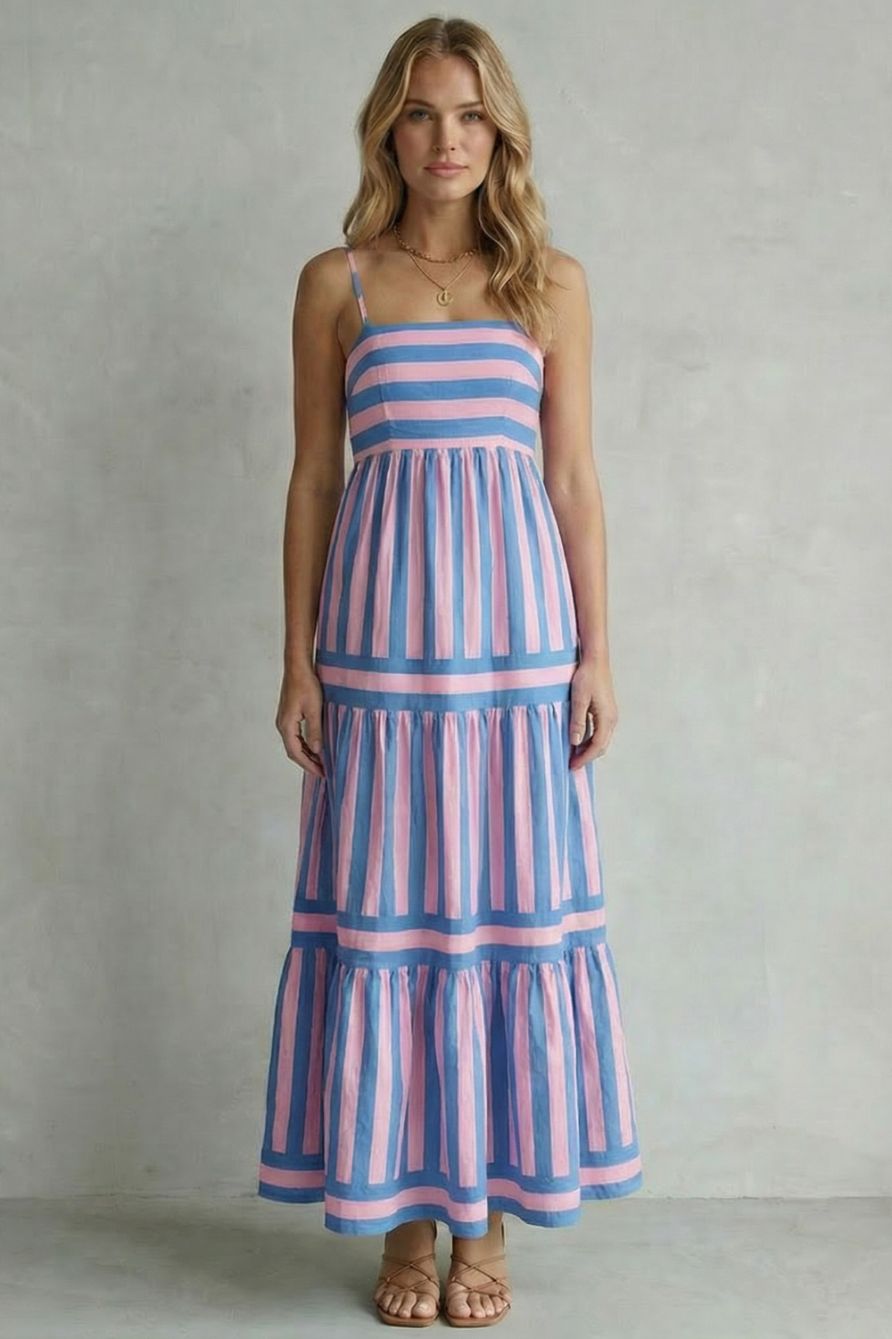 Full shot of a woman in a blue and pink striped strappy tiered maxi dress, featuring a flattering silhouette.
