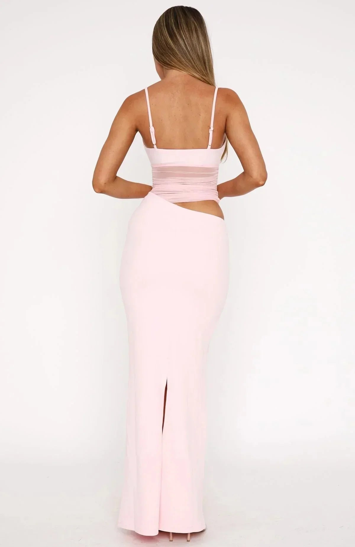 Back view of the light pink asymmetrical cutout ruched mesh maxi dress, revealing a subtle back slit.