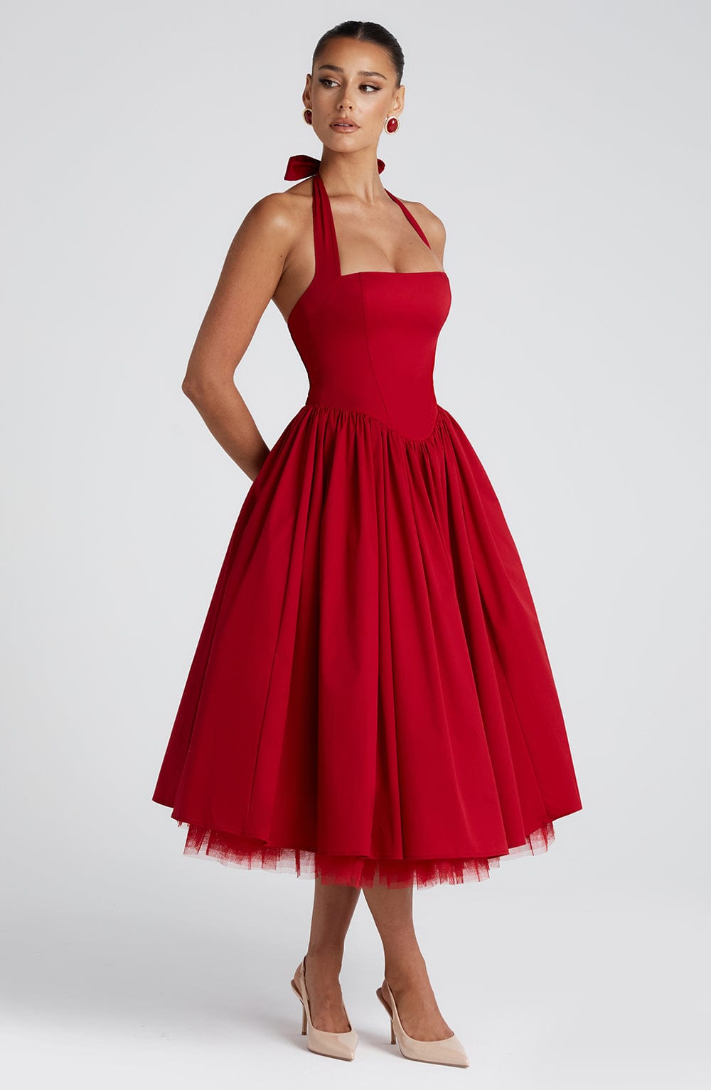 Side view of a red backless halter neck midi dress showcasing the full skirt and fitted bodice.