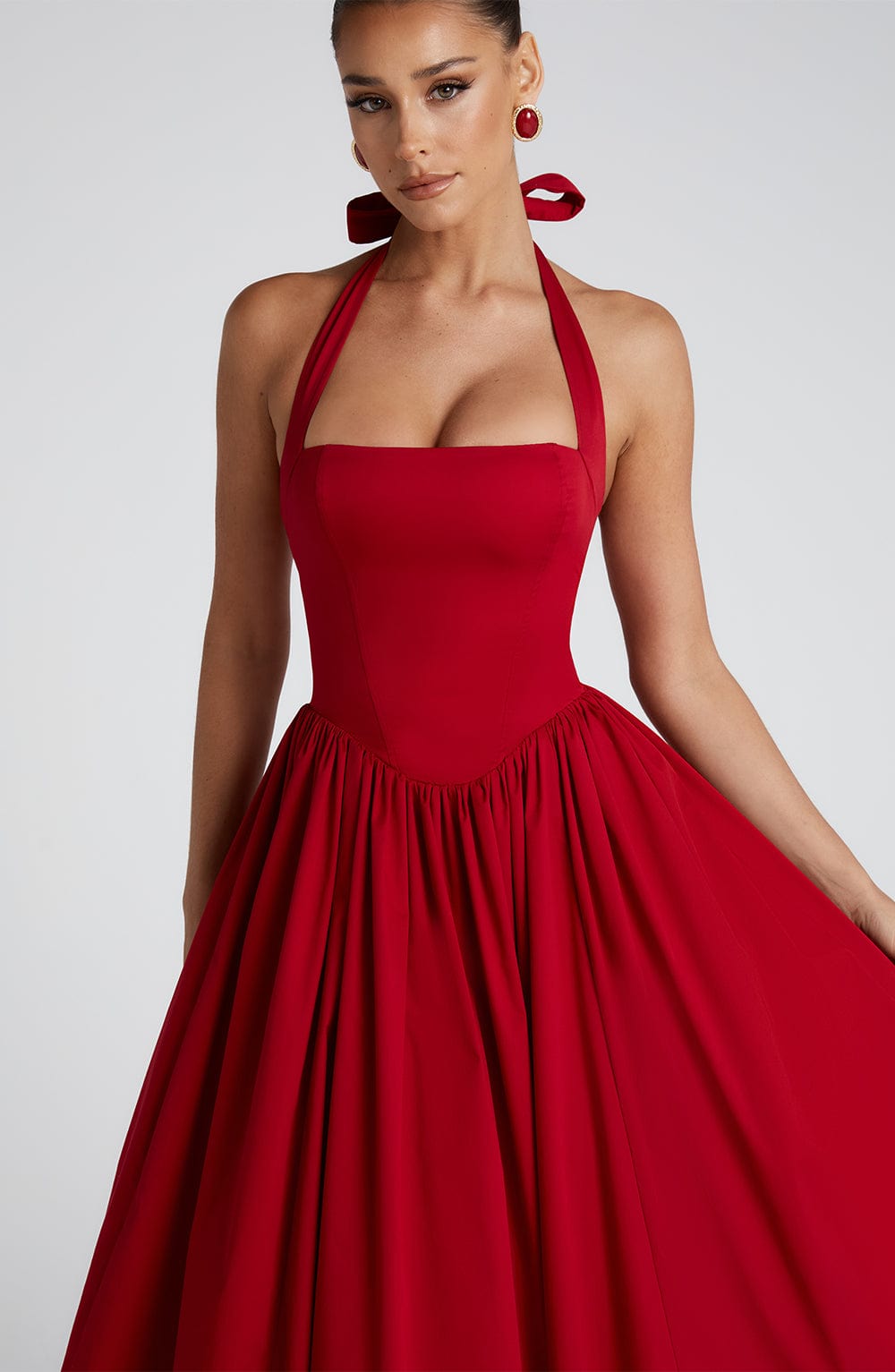 Close-up of the bodice of a red backless halter neck midi dress, showing the square neckline and fitted waist.