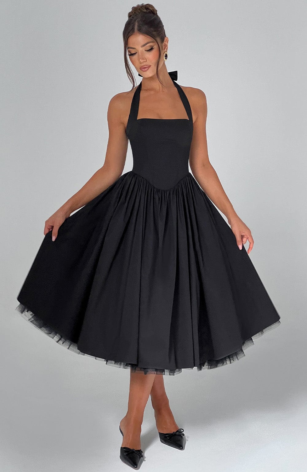 Front view of a black backless halter neck midi dress with a full pleated skirt and square neckline, suitable for elegant events.