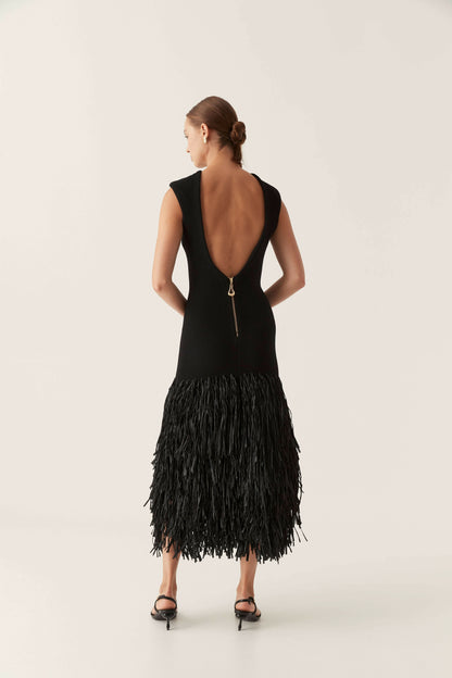 Back view of a black backless maxi dress featuring a gold zipper detail and a full fringe skirt, ideal for vacation outfits.