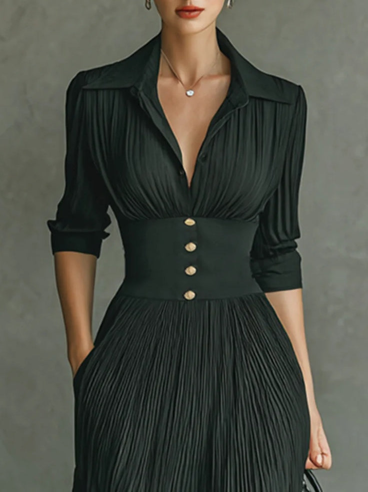 Close-up of black collared v-neck dress with pleated bodice and wide waist panel with buttons