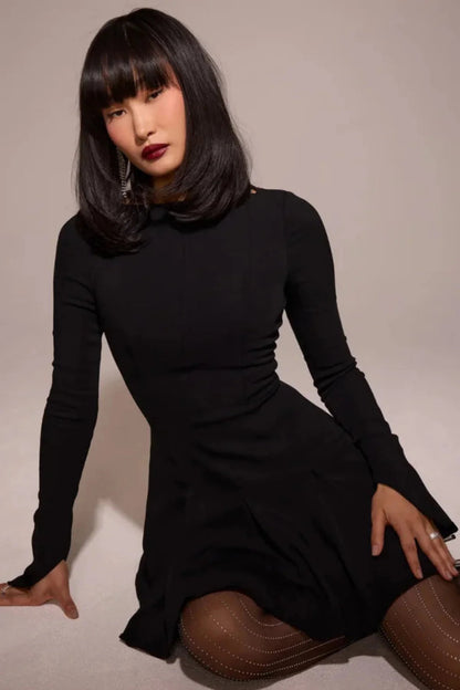 Model from behind wearing the Kouvr Fashion black long sleeve mini dress, showing the button details on the split cuffs
