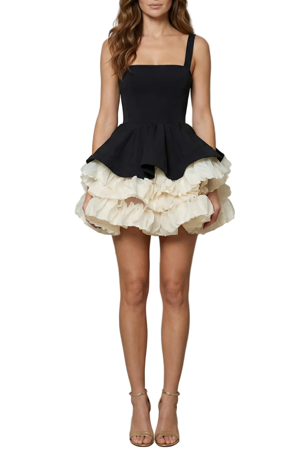 Front view of a woman wearing a black square neck mini dress with a voluminous cream ruffled skirt, paired with gold heels.