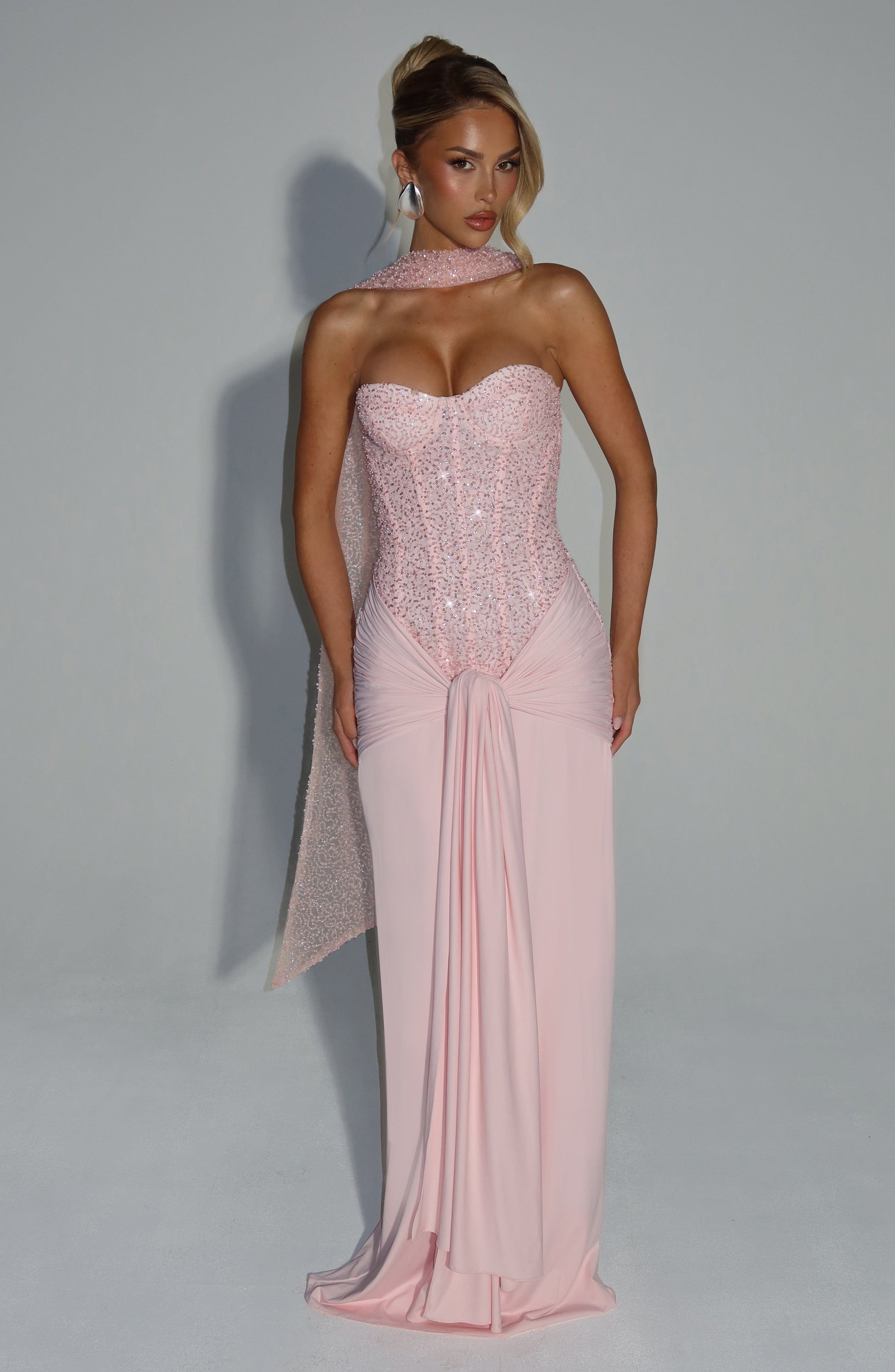 Full-length front view of a women's blush sequin corset strapless maxi dress with a cinched waist and elegant flowing skirt, ideal for formal events.