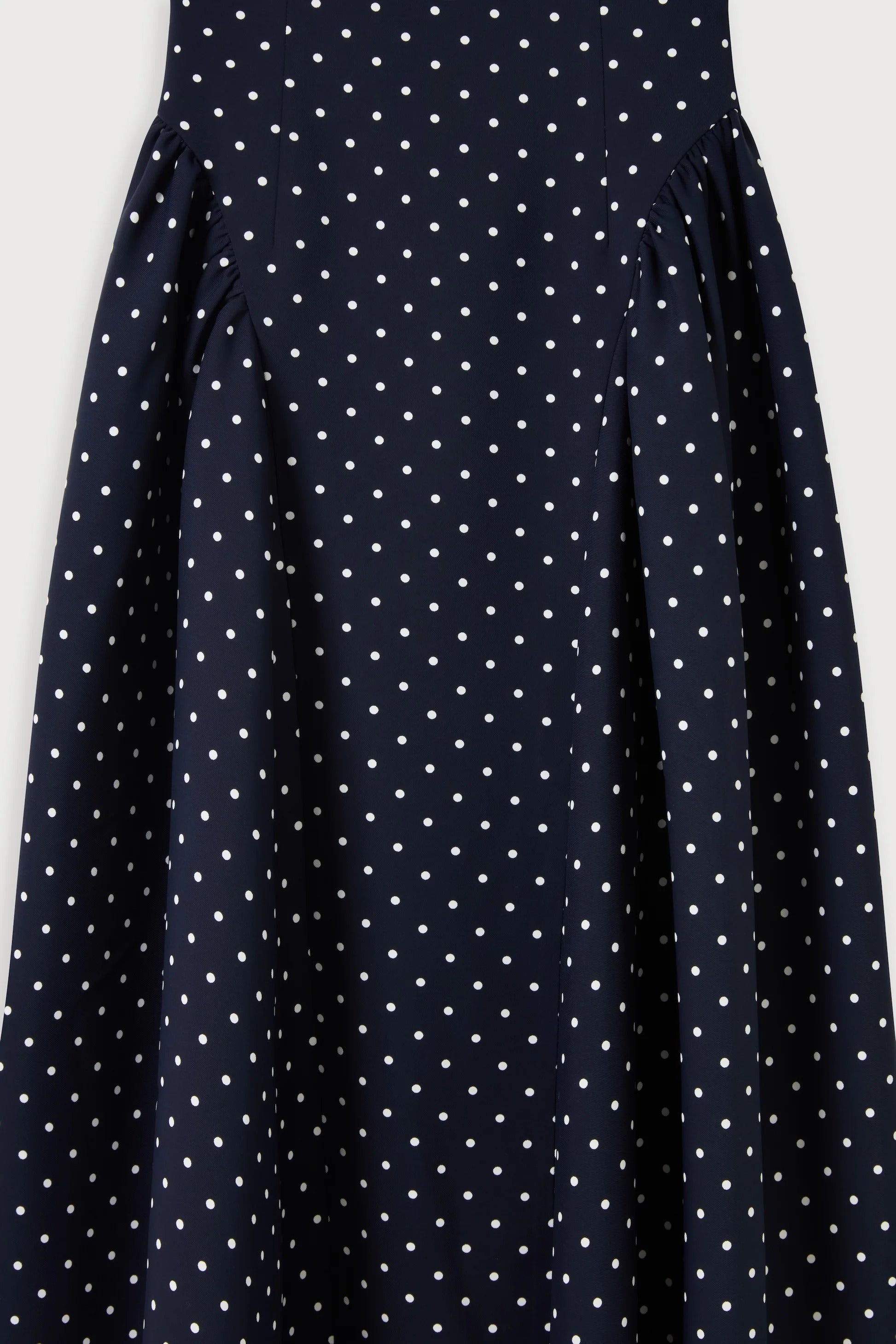 Close-up of gathered hip panels on navy polka dot midi summer dress showing draped fabric detail