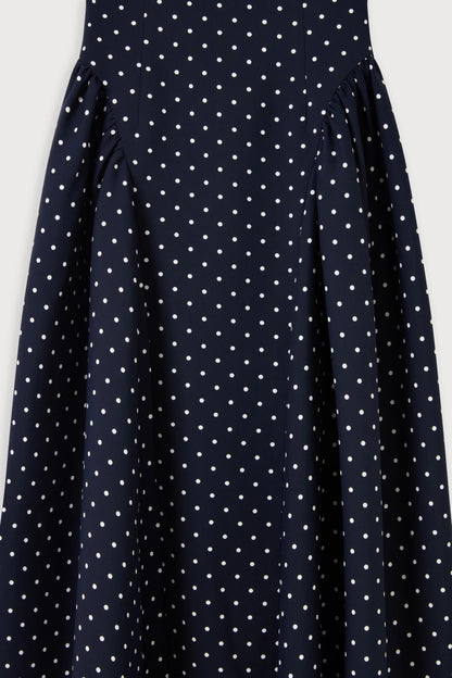 Close-up of gathered hip panels on navy polka dot midi summer dress showing draped fabric detail