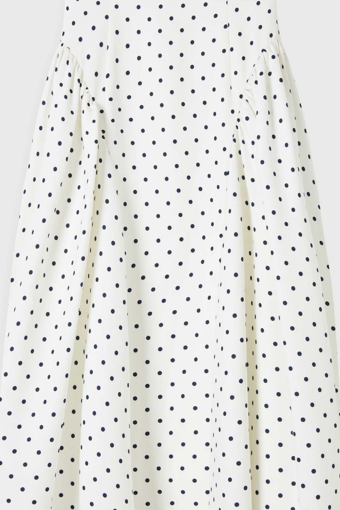 Fabric close-up of white polka dot midi dress showing gathered side panels and soft drape