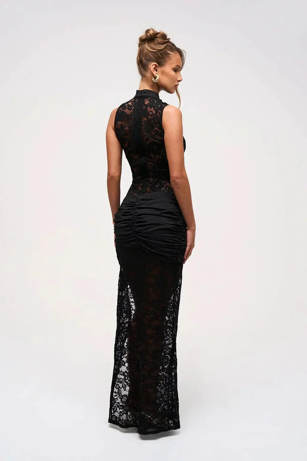 Back view of a black floral lace maxi dress, showing the ruched detail at the lower back and the sheer lace fabric.