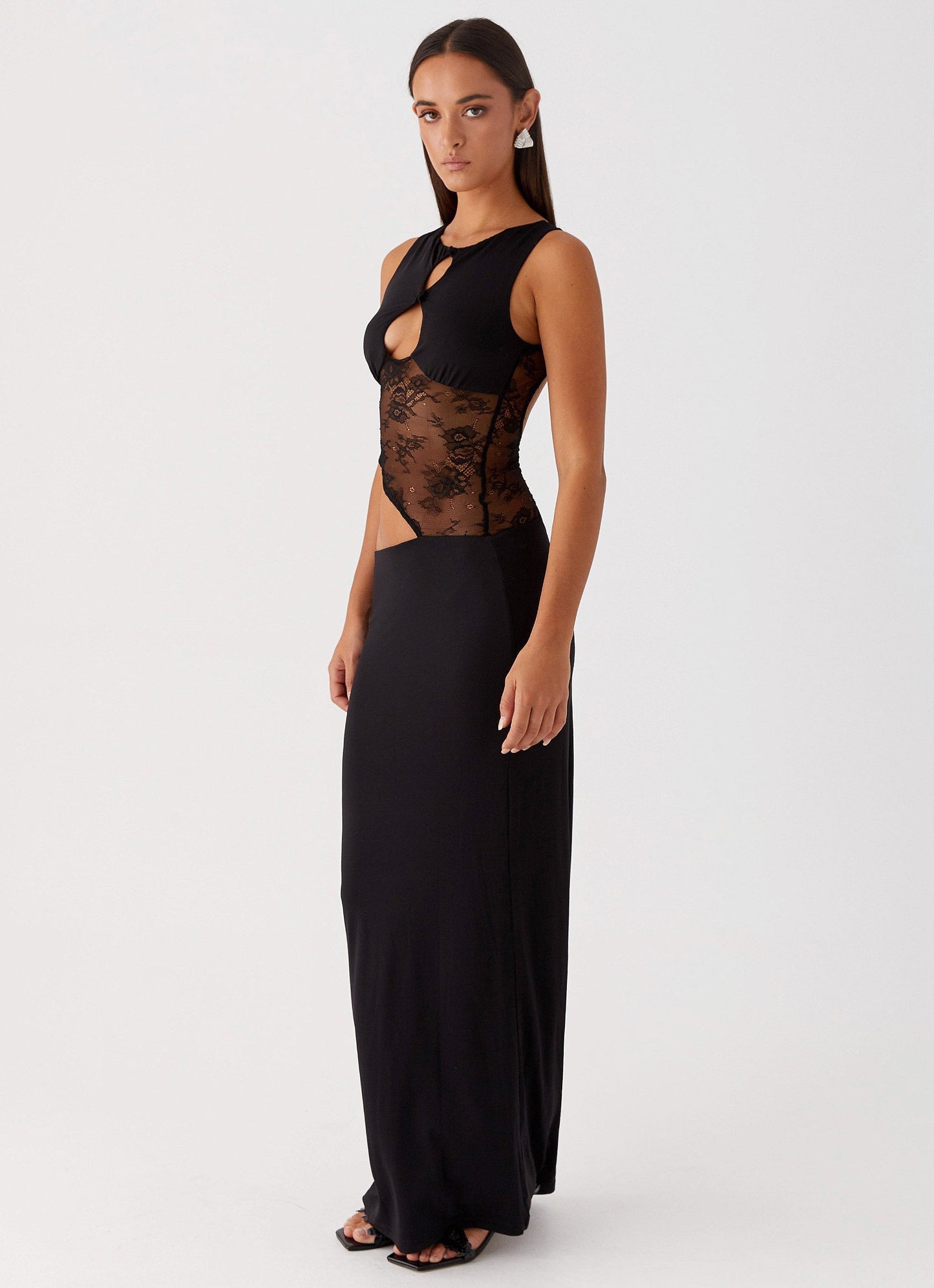 Angled view black cocktail maxi dress with lace torso panel and double keyhole cutouts