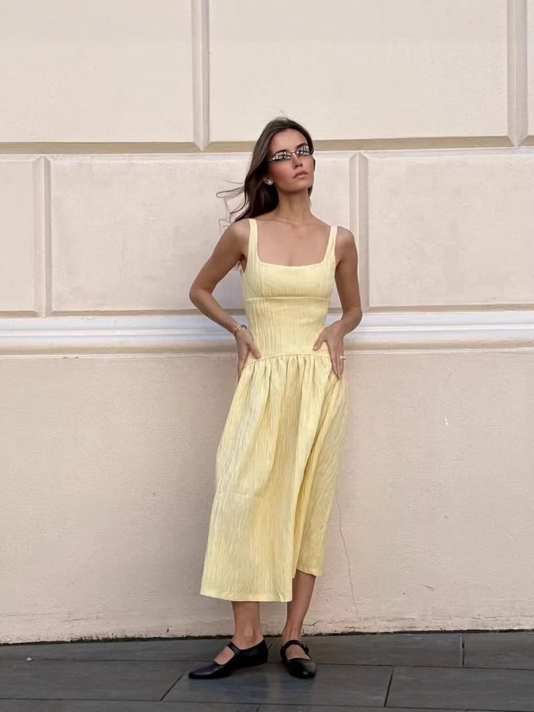 Women light yellow midi dress close-up showing square neckline edge, wide shoulder strap, textured fabric surface