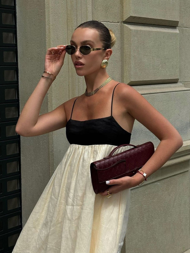 Close-up of a women's color-block maxi dress, showing the black spaghetti strap bodice and cream skirt fabric texture.