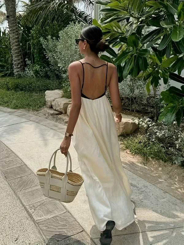 Back view of a women's color-block maxi dress, highlighting the open back design with black spaghetti straps and flowing cream skirt, perfect for vacation dresses.