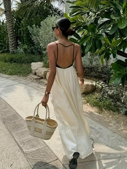 Back view of a women's color-block maxi dress, highlighting the open back design with black spaghetti straps and flowing cream skirt, perfect for vacation dresses.