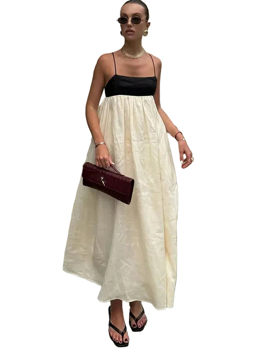 Women's color-block maxi dress with black spaghetti strap top and flowing cream skirt, styled with a maroon clutch and black sandals.