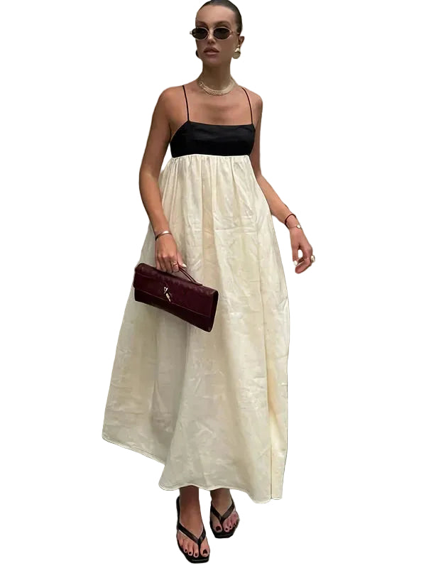 Women's color-block maxi dress with black spaghetti strap top and flowing cream skirt, styled with a maroon clutch and black sandals.