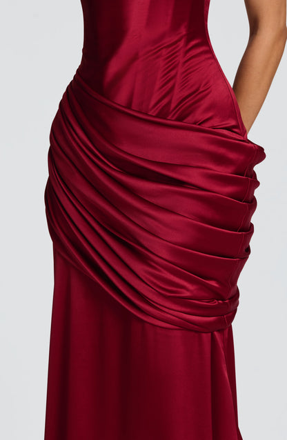 Detail of burgundy satin maxi dress ruched wrap overlay at hips with smooth skirt fabric