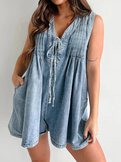 Close-up of the front tie and pleated bodice on a light wash denim romper with pockets.