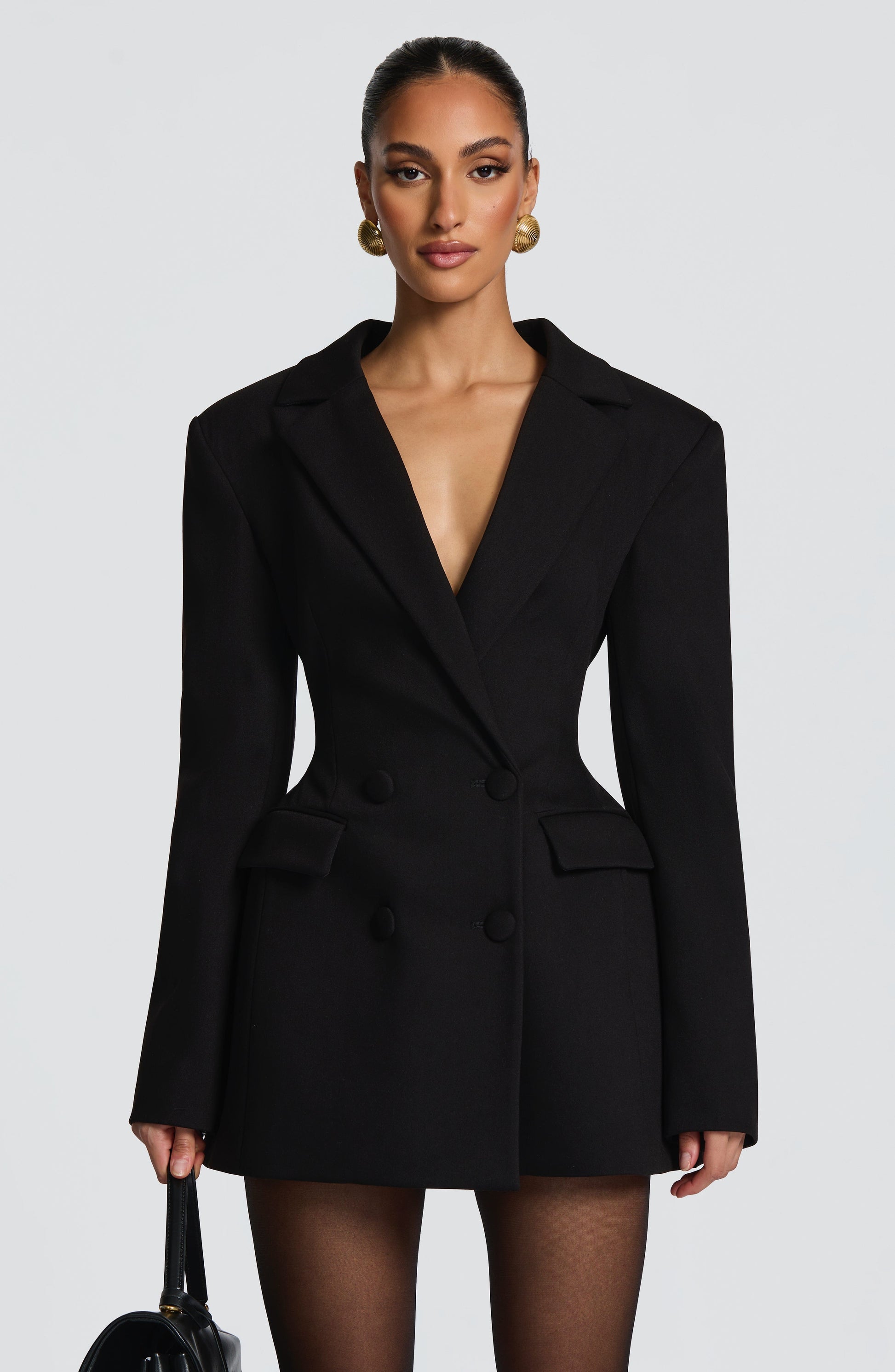 Front view of a black double-breasted mini dress with strong shoulder pads, showcasing a deep V-neck and four black buttons.