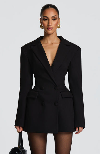 Front view of a black double-breasted mini dress with strong shoulder pads, showcasing a deep V-neck and four black buttons.