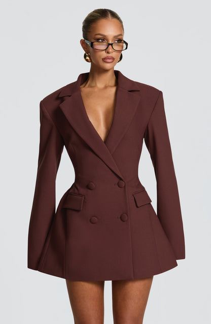 Front view of a brown double-breasted mini dress with structured shoulder pads, featuring a deep V-neck and four brown buttons.