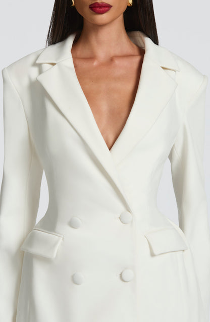 Close-up of the bodice of a white double-breasted mini dress, showing the lapels, deep V-neck, and four white buttons.