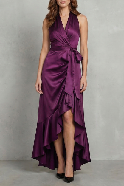 Vibrant plum purple satin halter wrap high-low maxi dress with a bow detail at the waist.