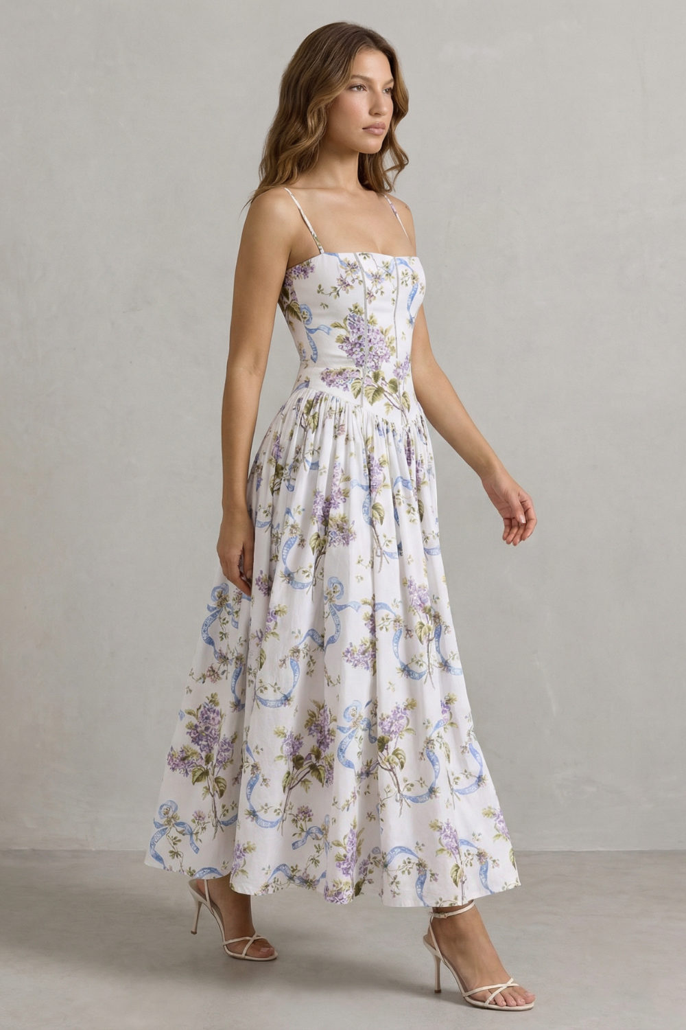Side profile of a women's floral midi dress, showcasing the flowing skirt and fitted corset bodice, suitable for wedding guests.