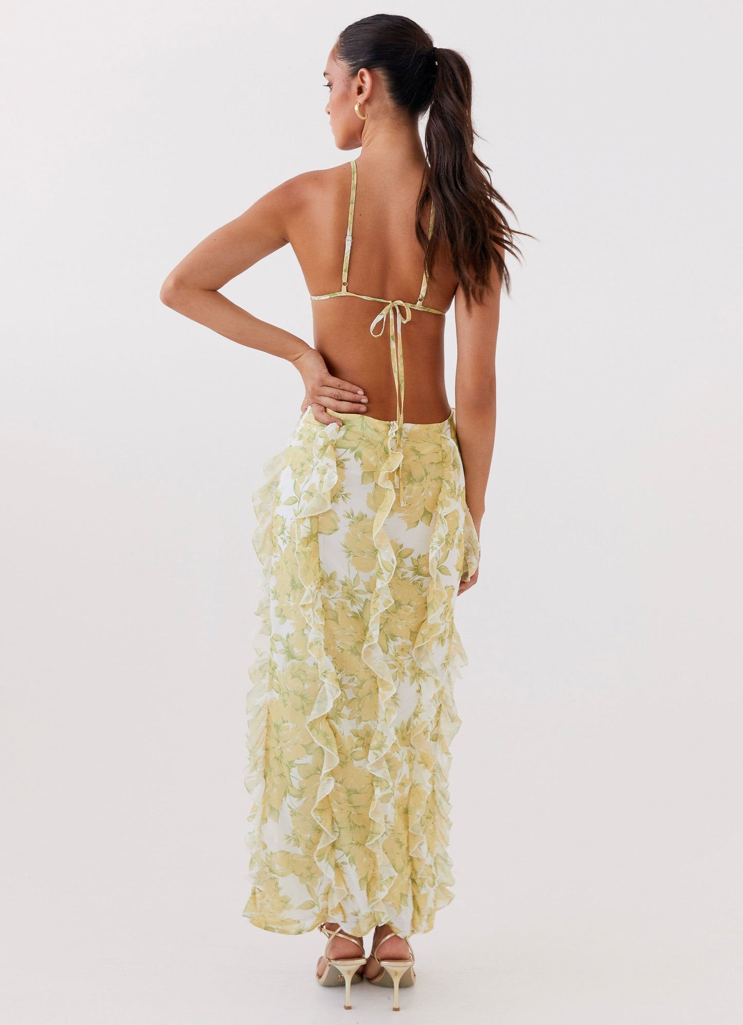 Back view of women's floral cut out ruffle tie front maxi dress showing tie-back detail and full ruffled skirt.