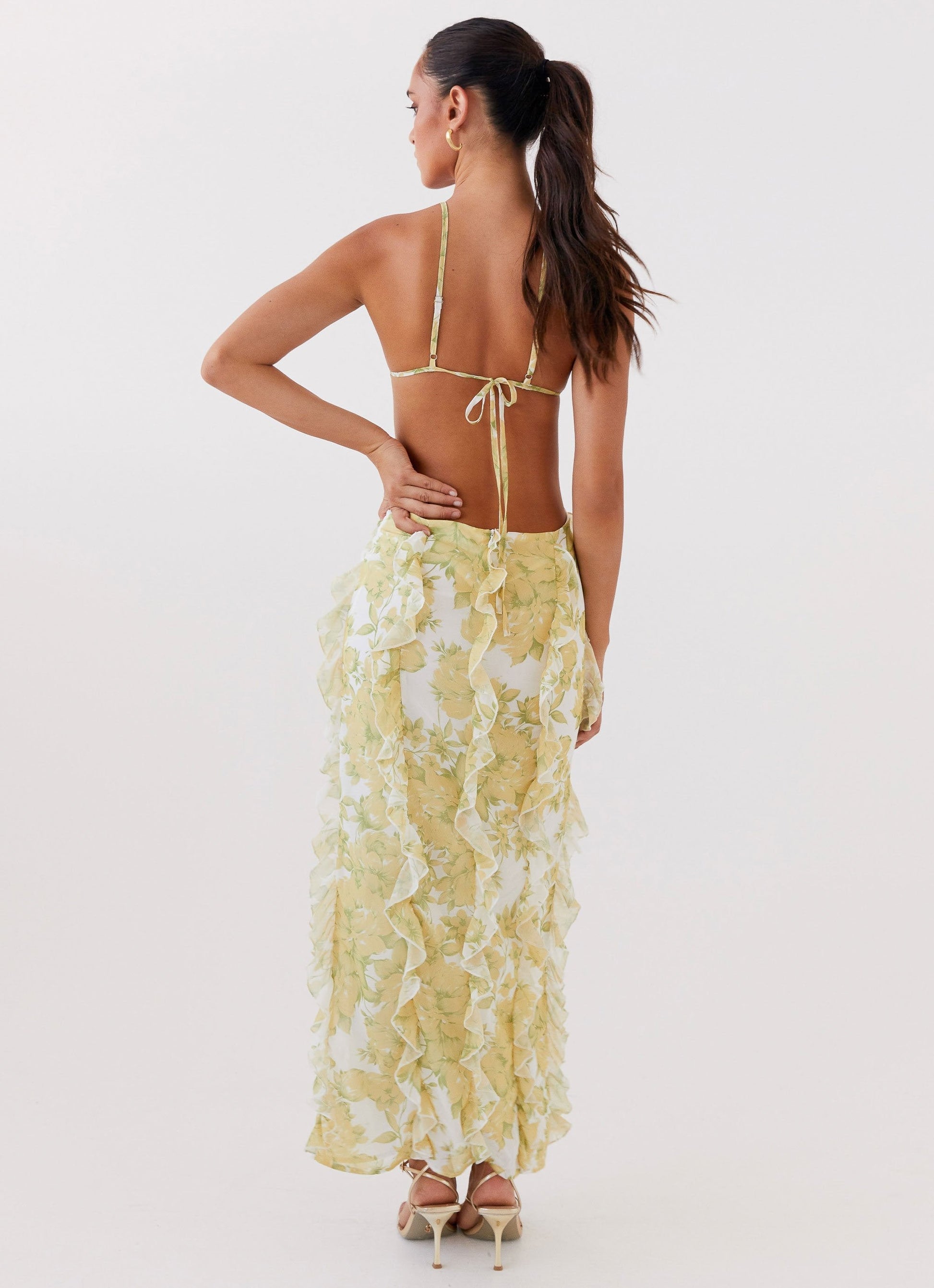 Back view of women's floral cut out ruffle tie front maxi dress showing tie-back detail and full ruffled skirt.
