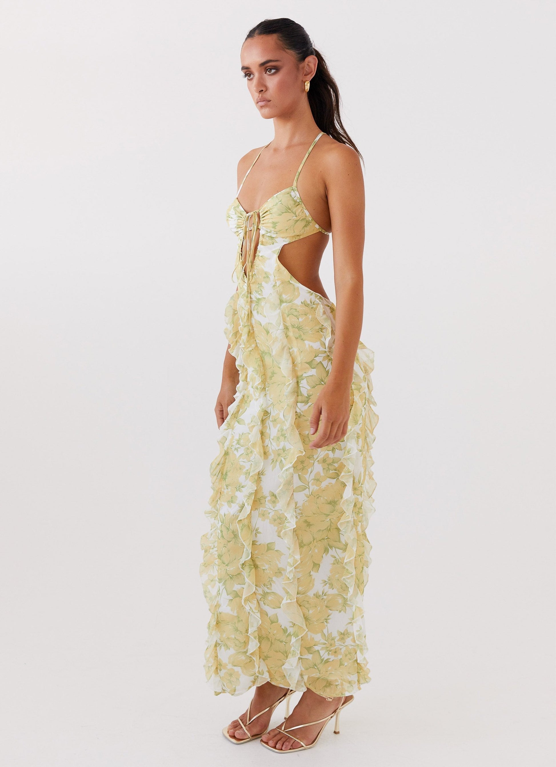 Side profile of women's floral cut out ruffle tie front maxi dress, showcasing the cut-out waist and flowing ruffles.