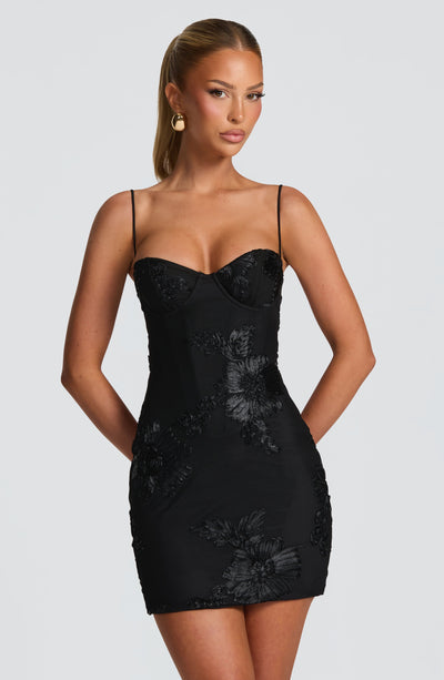 Front view of a black floral embroidered corset tie-back mini dress with spaghetti straps, a chic option for wedding guests.