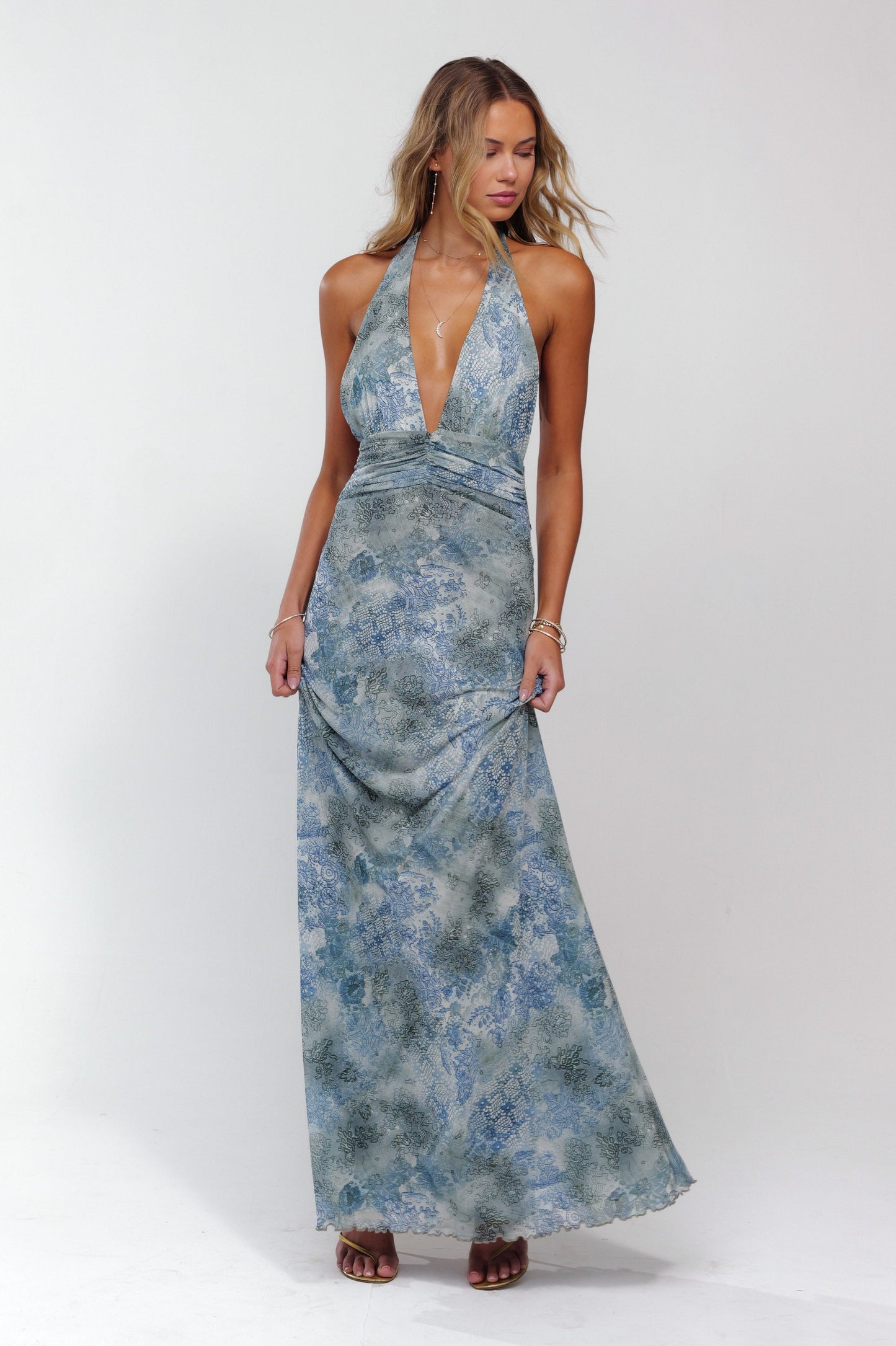 Women's halter neck maxi dress in a light blue and grey floral pattern, with a deep v-neck and ruched details, perfect for a wedding guest.