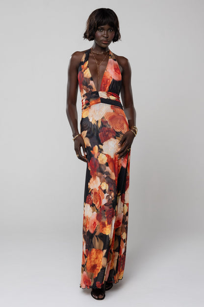 Elegant women's floral halter maxi dress in vibrant orange, red, and black, featuring a plunging neckline and flowing skirt, ideal for vacation outfits.