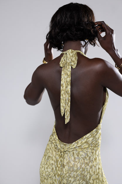 Back view of the green and yellow abstract print halter maxi dress, showcasing the tie-neck closure and open back, an elegant option for wedding guests.