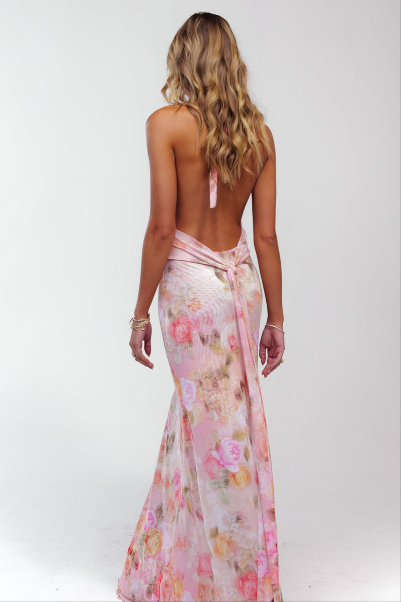 Back view of a women's pink floral halter maxi dress, showcasing the open back and tie detail.