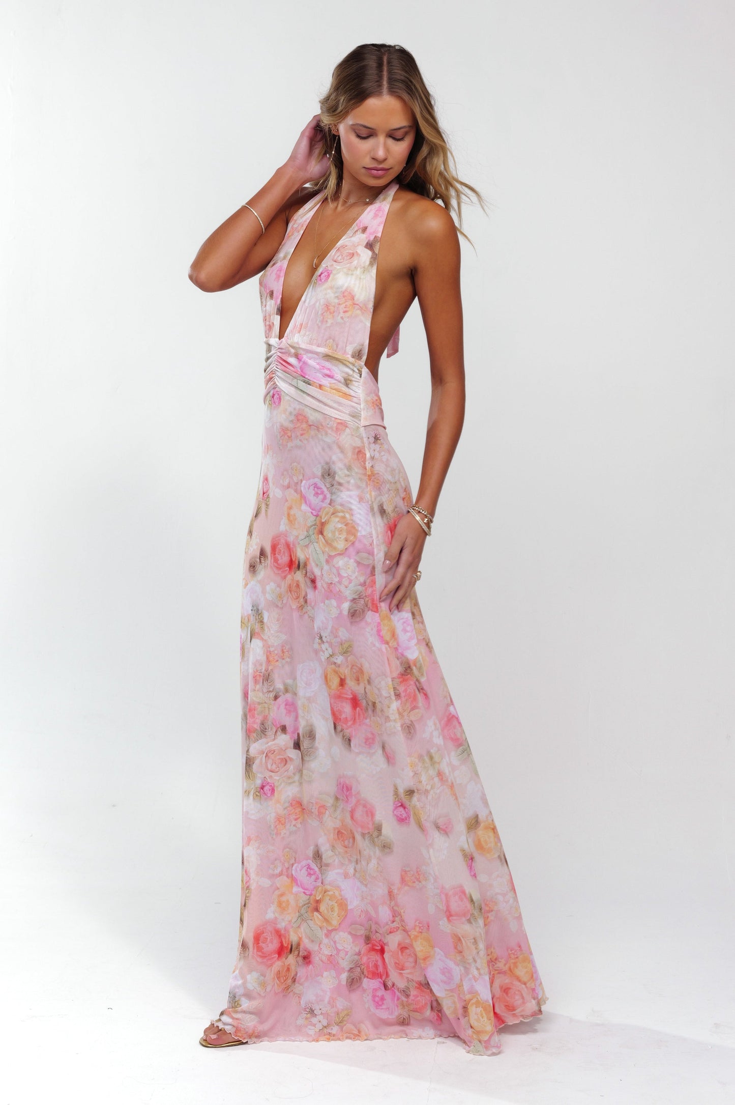Side profile of a women's elegant pink floral halter maxi dress with a flowing skirt and deep V-neck.