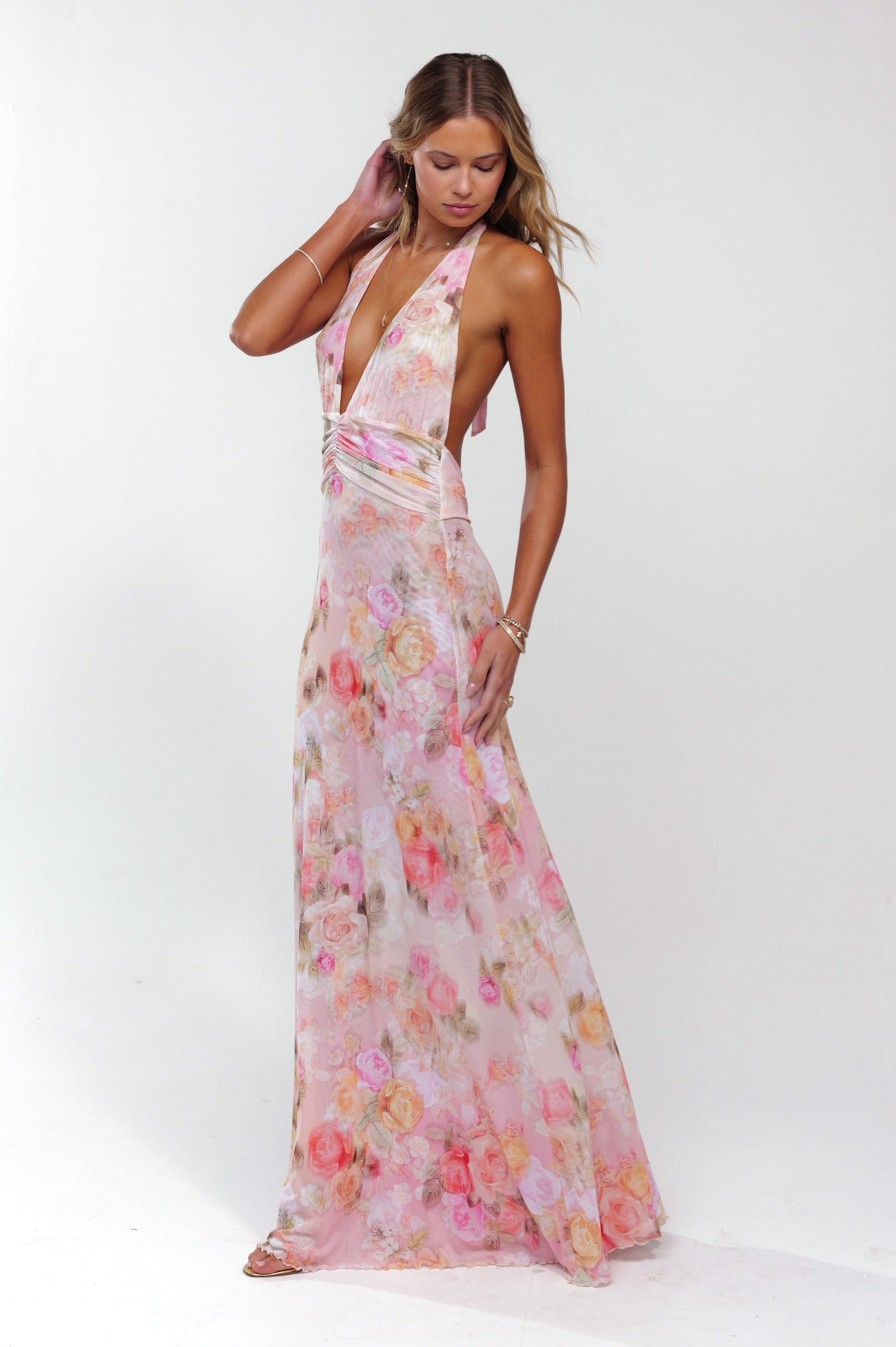 Side profile of a women's elegant pink floral halter maxi dress with a flowing skirt and deep V-neck.